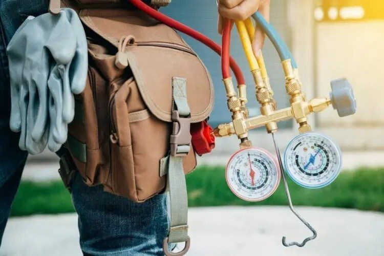 Technician's refrigerant gauges during an AC repair